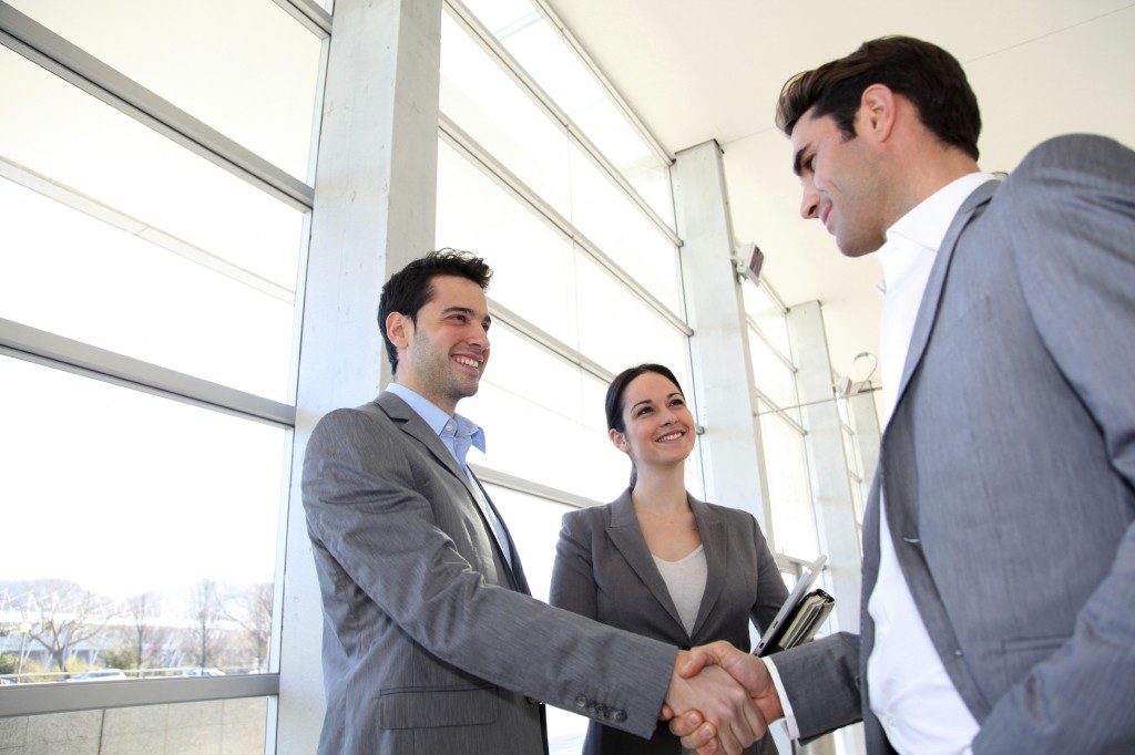 Business partners shaking hands in meeting hall